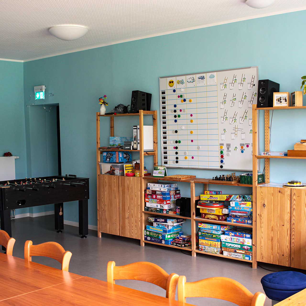 Ein Gruppenraum mit Tischkicker, Anbauwand, Sofa, Tisch und Stühlen.