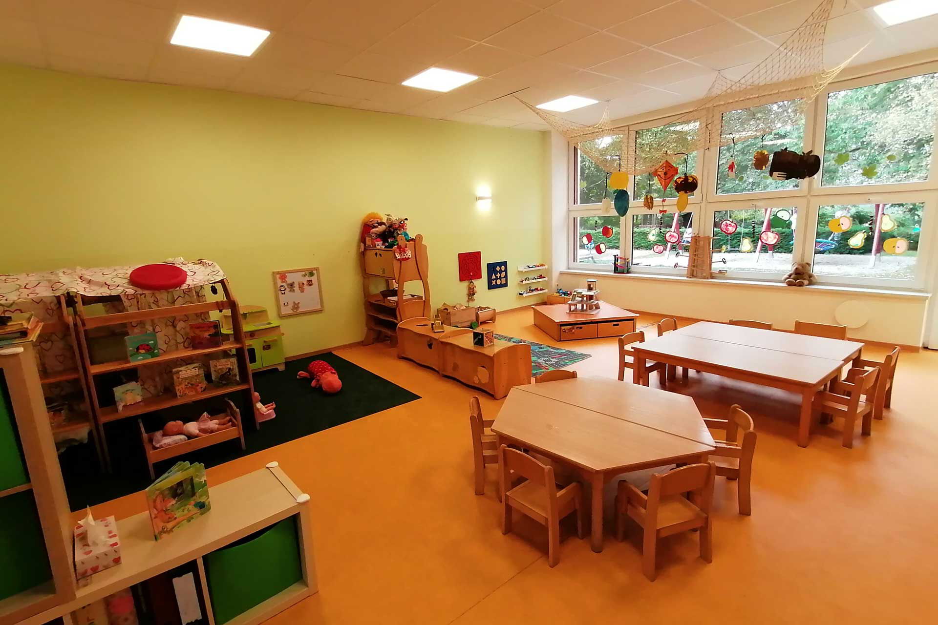 Gruppenzimmer Spielecke Im Gruppenzimmer stehen zwei Tische mit Stühlen, eine Spielecke und verschiedene Baumaterialien.