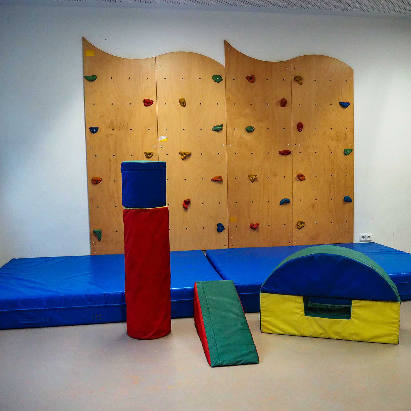Im Sportzimmer sind eine Kletterwand, Sportmatte und viele Schaumstoffkissen.
