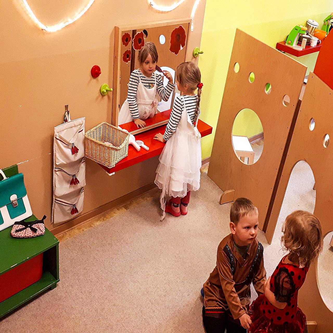 In der Spieleecke im Schloss befindet sich ein Wandspiegel und eine Sitztruhe. Es spielen drei Kinder im Schloss.