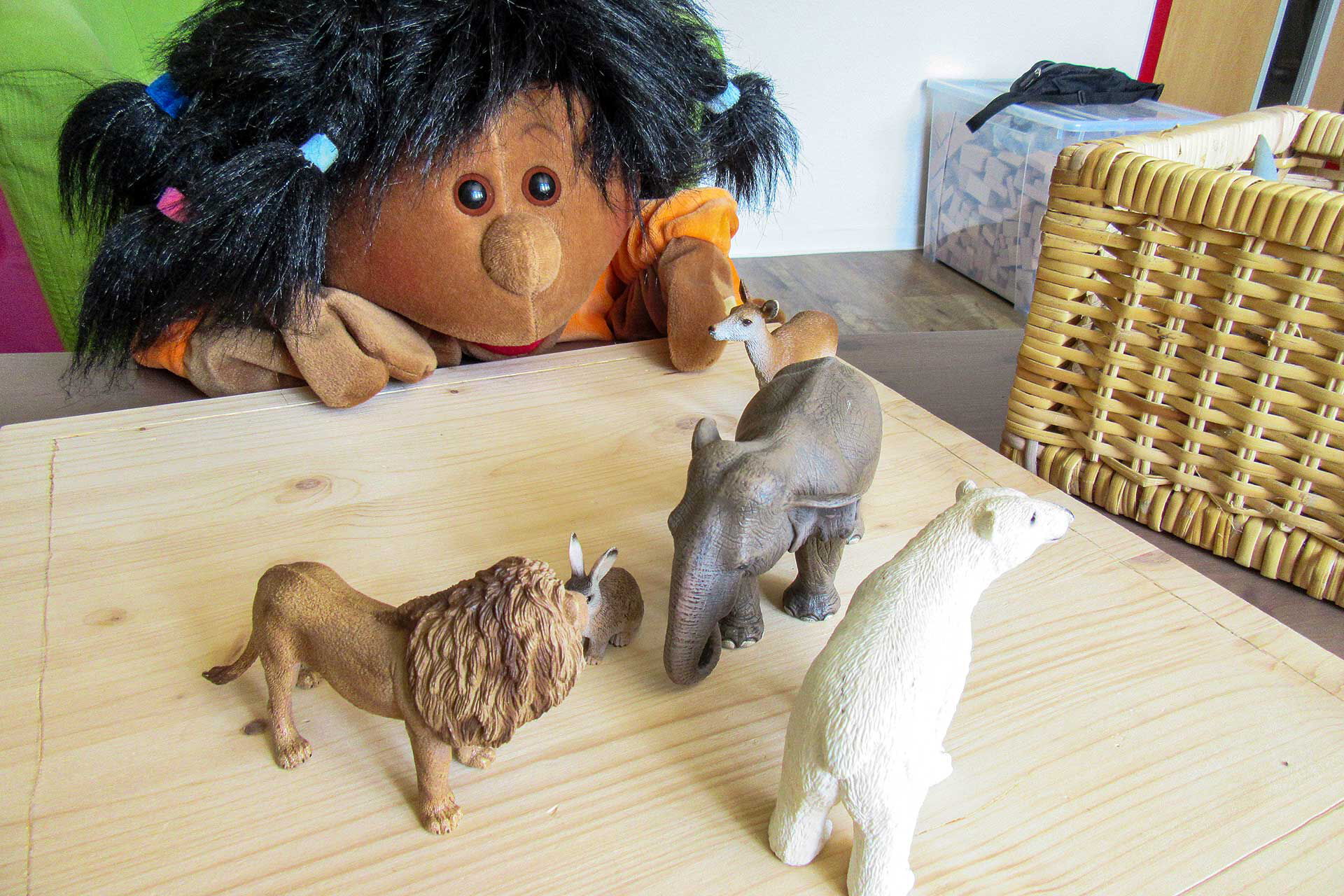 Entwicklungsthemen der Kinder Auf einem Holztisch stehen ein Hase, Reh, Elefant, Löwe und Eisbär.